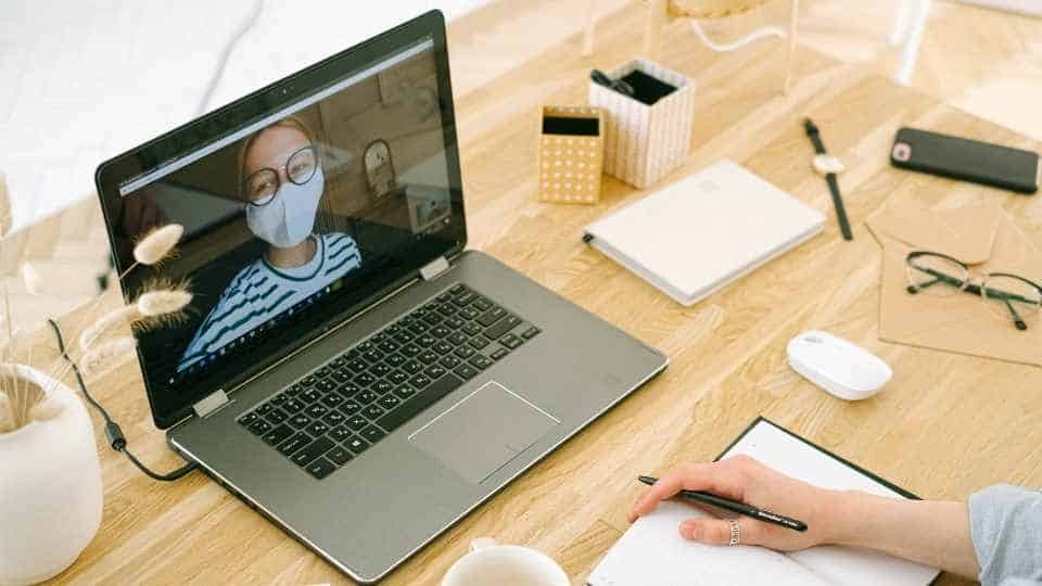 Telefonkonferenz-Zuschaltung mit Frau mit Corona-Maske