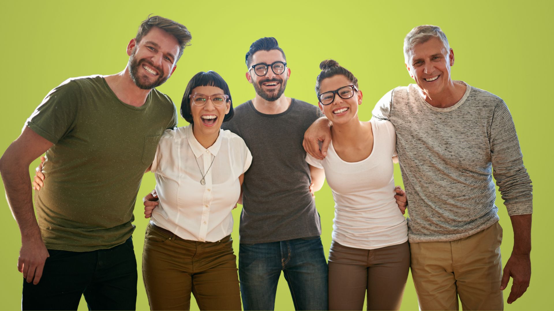 Foto mit 5 Menschen unterschiedlichen Alters, die sich zusammengehörig fühlen und die Arme umeinander gelegt haben. Im Teamkontext arbeiten sie generationenübergreifend gut zusammen.